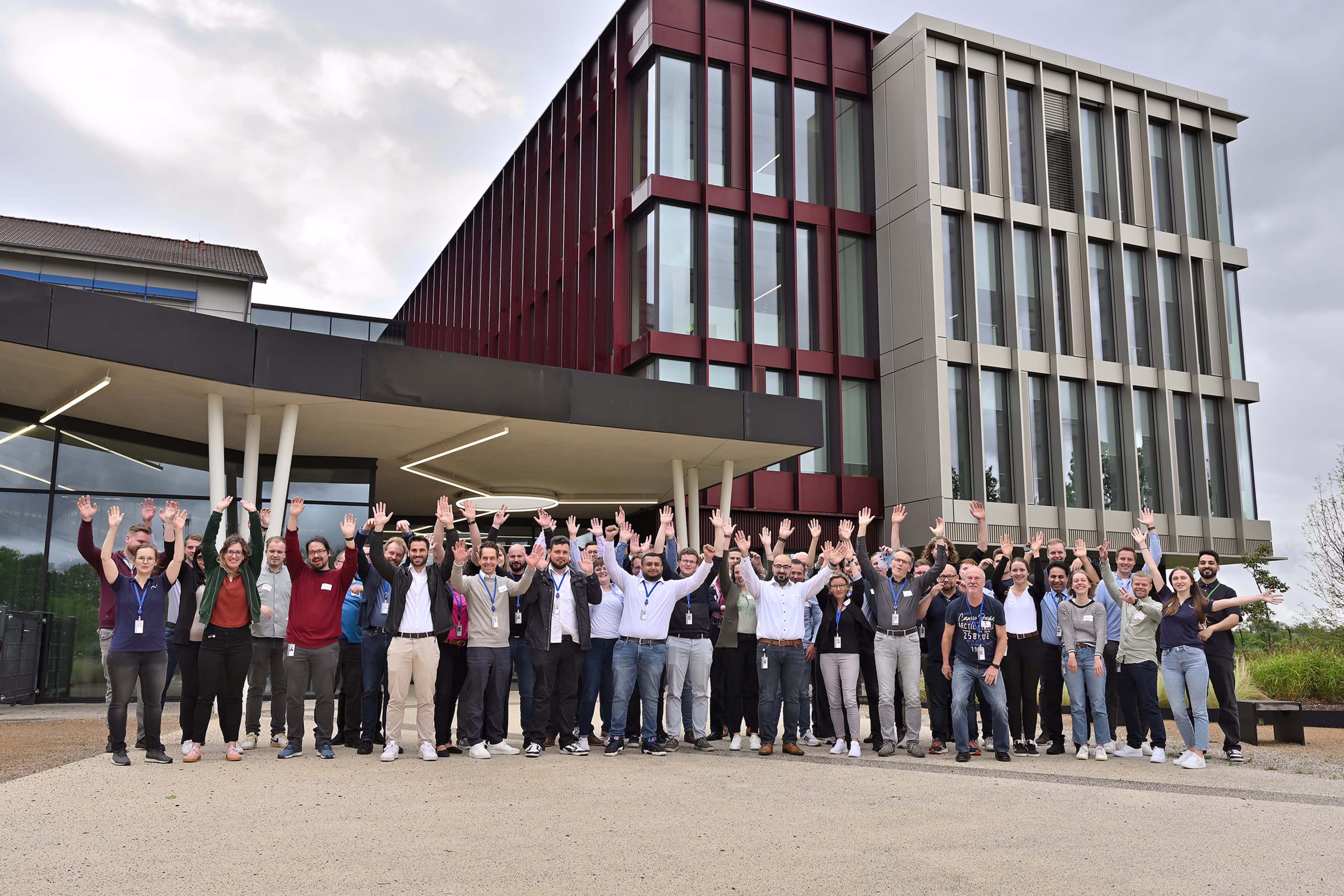 Eine Gruppe von Menschen steht mit erhobenen Armen vor einem Gebäude