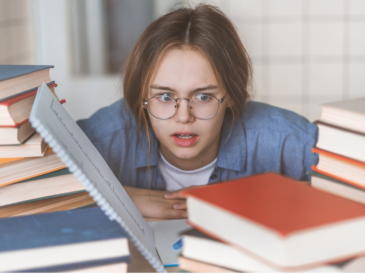 the-upset-woman-sitting-with-closed-eyes-among-textbooks-and-laptop-picture-id1153593912