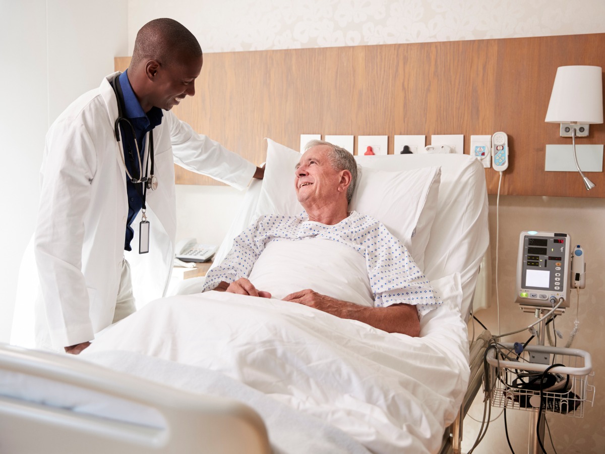 doctor-visiting-and-talking-with-senior-male-patient-in-hospital-bed-picture-id1147976228