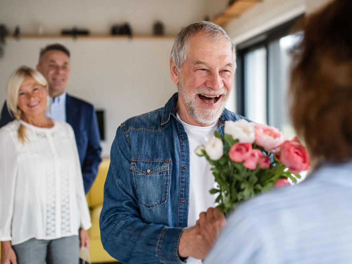 group-of-senior-friends-at-dinner-party-at-home-greeting-picture-id1211096668