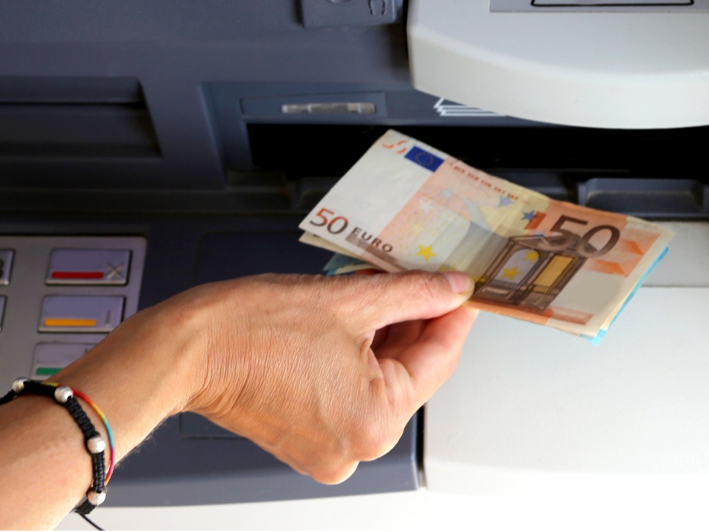 girl-while-withdrawing-50-euros-banknotes-from-an-atm-picture-id855731212