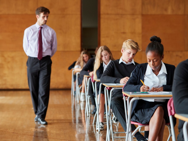 teenage-students-sitting-examination-with-teacher-invigilating-picture-id887313758