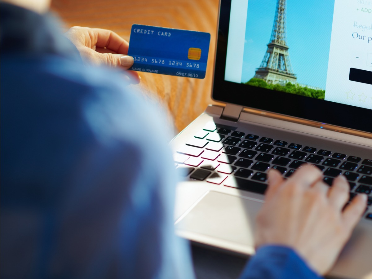 woman-with-online-travel-site-on-laptop-holding-blue-credit-card-picture-id1152346432