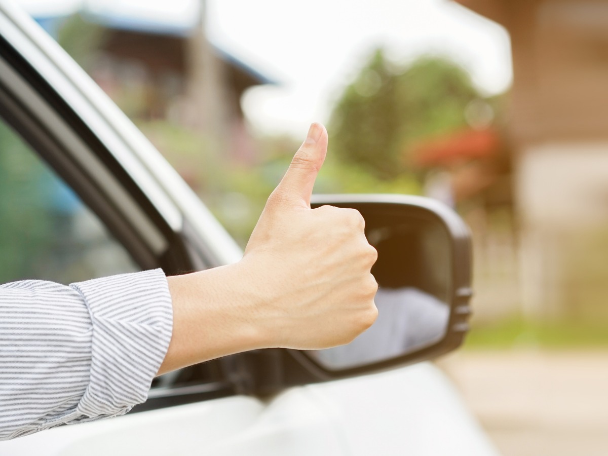 close-up-driver-man-hand-showing-thumb-up-through-cars-window-for-picture-id1035978062