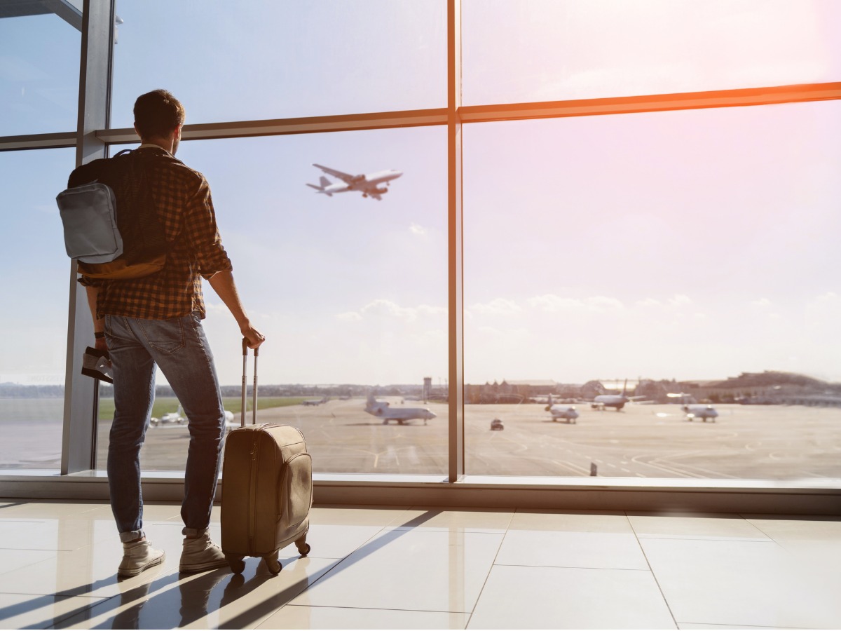 serene-young-man-watching-plane-before-departure-picture-id619394704