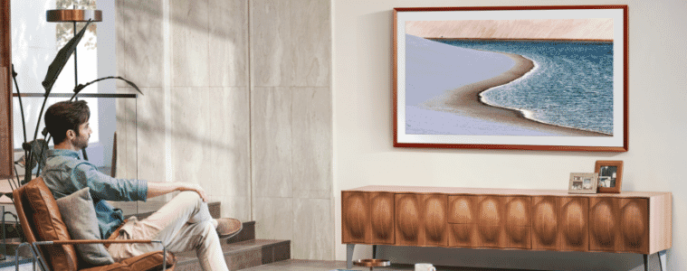 A man sits in a chair in his living room and looks at his lifestyle TV showcasing art