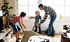 A dad and his two kids cleaning up the living room