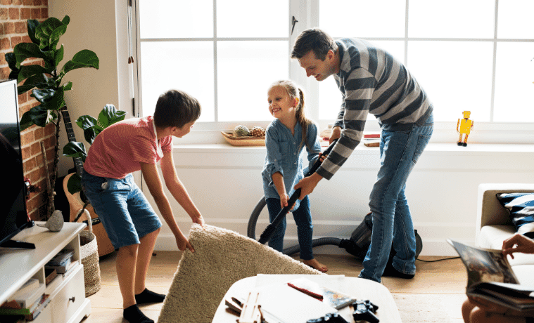 A dad and his two kids cleaning up the living room