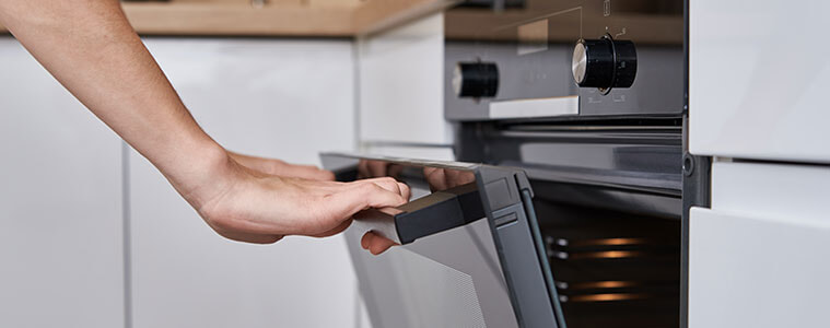 Woman opens the door of an electric oven