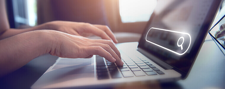 A person types a query into their home office laptop