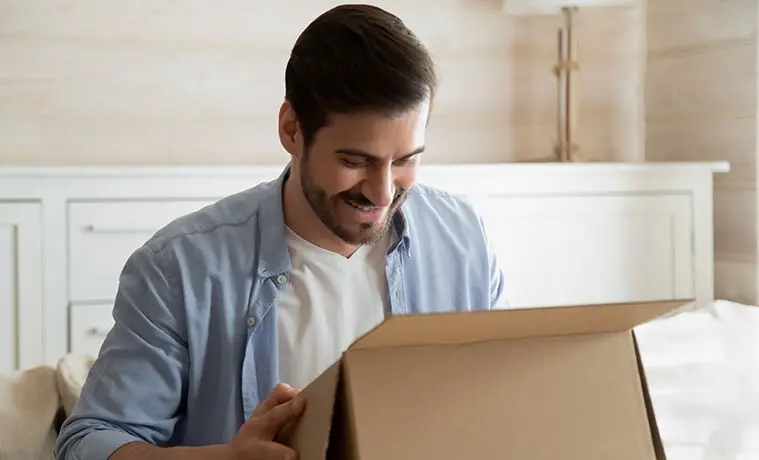 An overjoyed male customer unpacks a delivery box