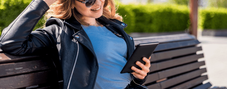 a woman sitting outside using an ereader 