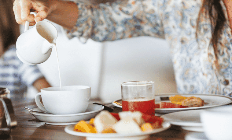 Woman pouring milk in mug from kettle Breakfast time