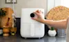 A hand adjusting a black dial on a white air fryer next to power point