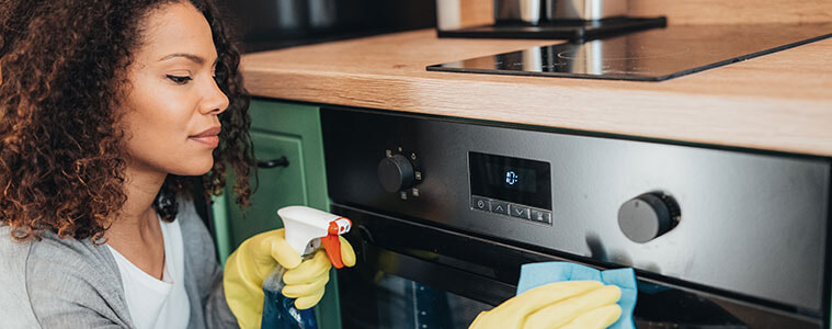 a woman cleaning the outside of her oven 