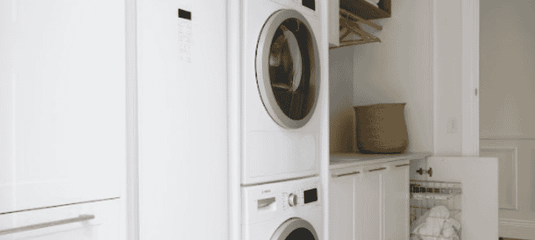 Spacious modern laundry with stacked front loading washing machine and dryer set into fresh white cabinetry