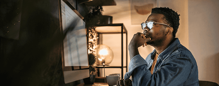 A man works at the desktop computer in his home office at night