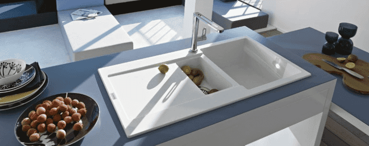 A white sink in a kitchen with blue benchtops