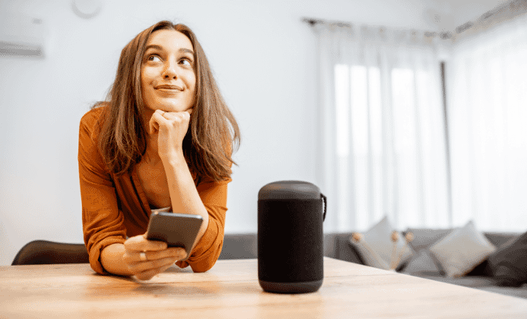 Woman at home with her smartphone and smart wireless speaker 