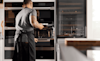 A man putting food into a Miele oven 
