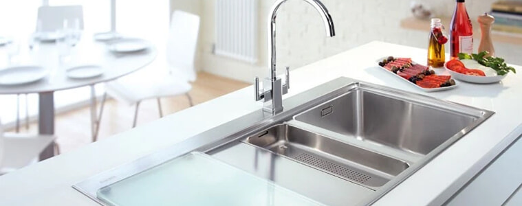 A silver stainless steel sink in a white kitchen