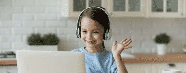 A young girl using a laptop and headphones to study