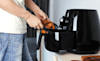 a man taking fried chicken out of the air fryer 