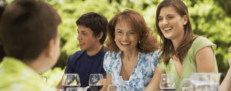 Happy family having lunch together at table in backyard
