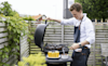 Man cooks ribs on a barbecue in his backyard