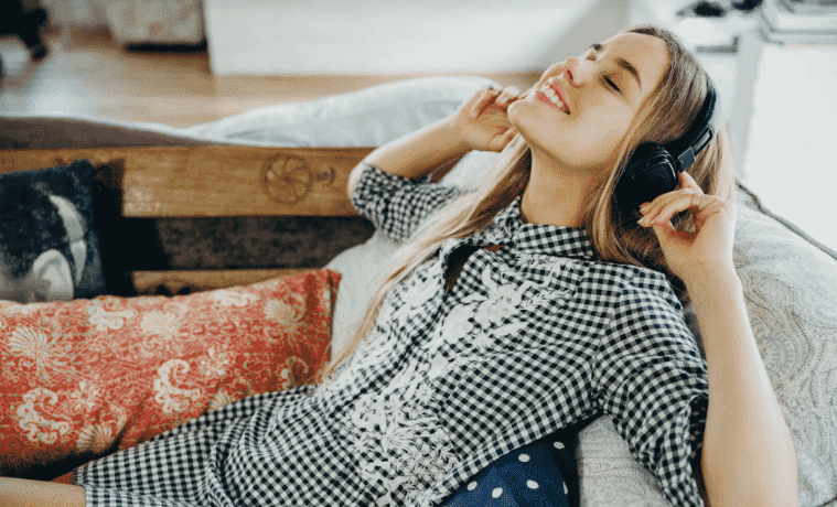 A girl lays on the couch and listens to music with her headphones
