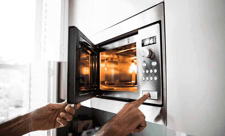 A person presses the button to open their microwave