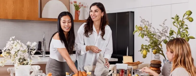 A group of friends sit down to enjoy a meal prepared from the Samsung French door fridge