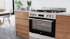 Beko stainless free standing oven in a kitchen with wooden cabinetry.