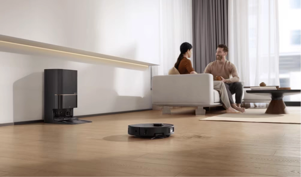 Image of a Dreame Robot Vacuum cleaning a hardwood living room while couple sit on the couch.
