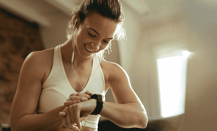 Woman in activewear checks her heart rate on her fitness tracker on her wrist