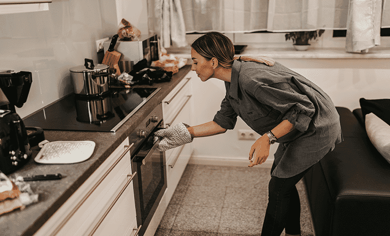 A woman bends to open the oven door in her stylish new kitchen