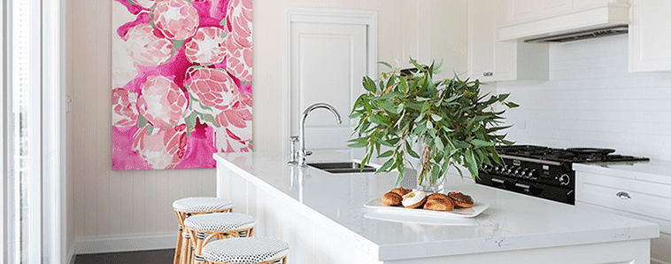 Contemporary white kitchen island with pendant lights and pink painting