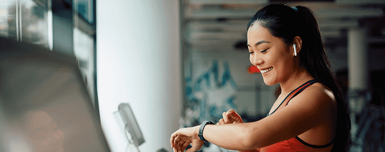 Woman at the gym on a treadmill checks her heart rate on her fitness tracker