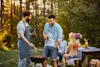 Two men standing and talking next to a small charcoal BBQ