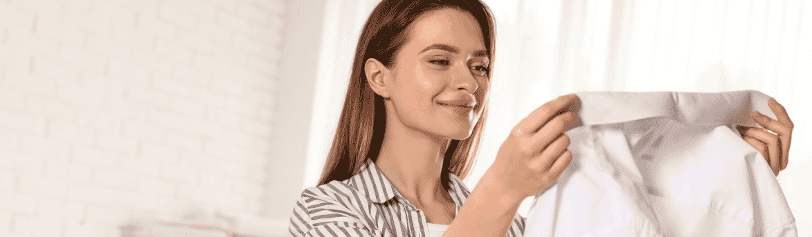 Image of woman smiling as she holds an ironed shirt.