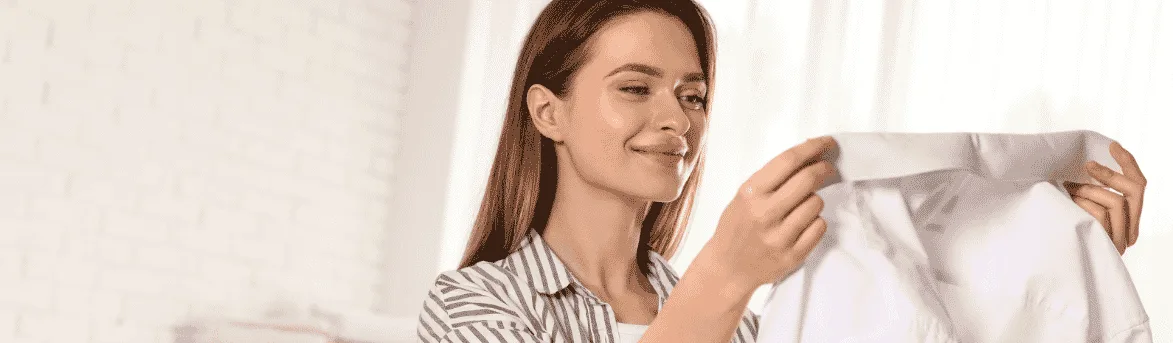 Image of woman smiling as she holds an ironed shirt.