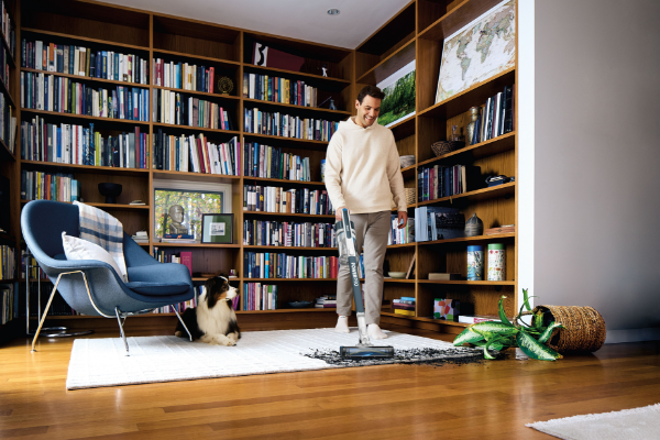 Man using Shark stick vacuum to vacuum living room effortlessly. 