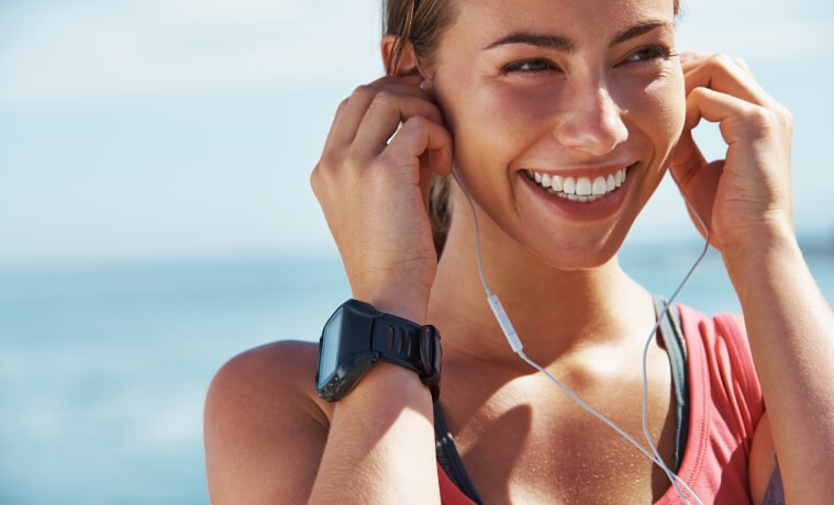 A cheerful young woman puts her earphones in