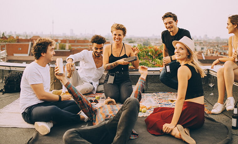 Friends enjoying music from an outdoor speaker during a rooftop party