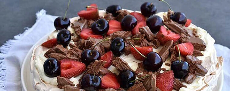 A pavlova topped with Tim Tams cherries and strawberries