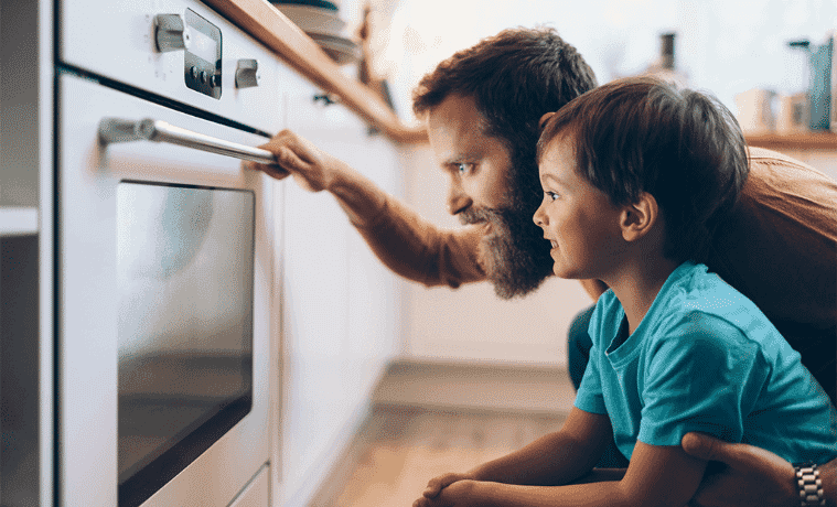 Dad has his arm around his small son as they intently watch their pyrolytic oven blast away the grime