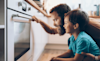 Dad has his arm around his small son as they intently watch their pyrolytic oven blast away the grime