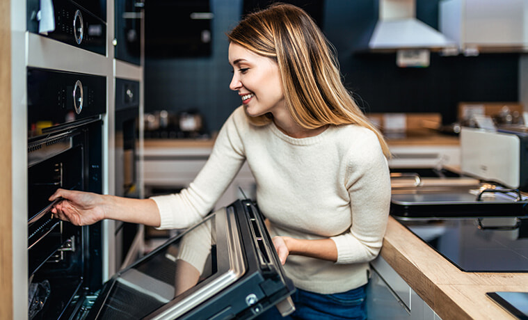 Woman opens the door of the wall oven in her modern kitchen