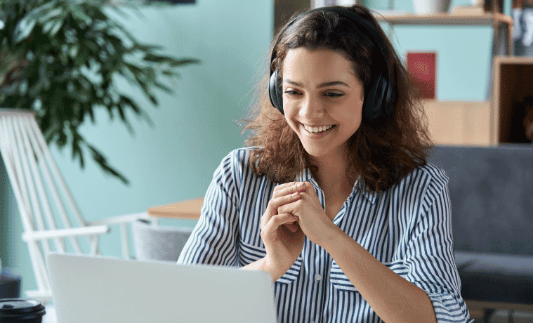 a girl sitting at her desk doing uni work on her laptop while listening to music with her noise cancelling headphones 