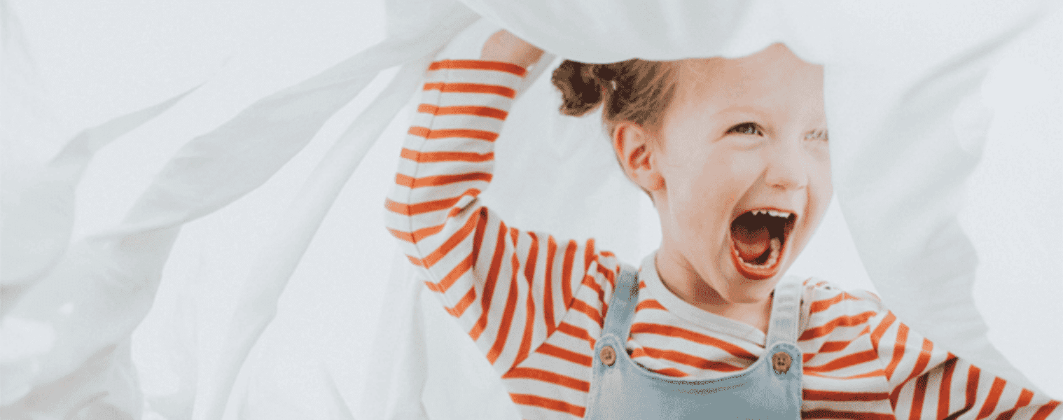 A little girl plays with freshly laundered bed sheets